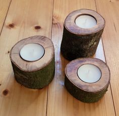 three wooden candles sitting on top of a wooden table next to each other with one candle in the middle