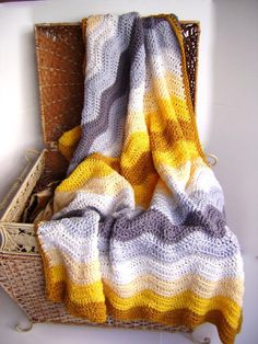 a yellow and gray blanket sitting on top of a wooden shelf next to a basket