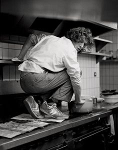 a man bending over in the kitchen preparing food