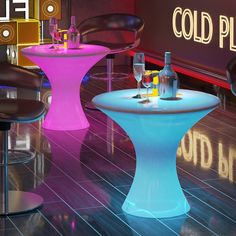 there are several different colored tables and chairs in this room with neon lights on the floor