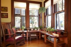 a room filled with lots of windows next to wooden furniture and potted plants on top of them