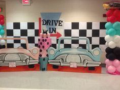 some balloons and cars are on display in a room with black and white checkered walls