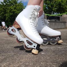 a person riding roller skates on top of cement ground with trees in the background