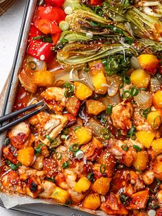 a sheet pan filled with chicken, vegetables and sesame seed sauce next to chopsticks