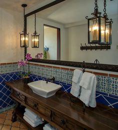 a bathroom with blue and white tiles on the walls, sink and mirror in it