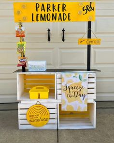 an outdoor lemonade stand made out of crates with yellow and white signs on it