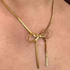 Unleash your wild side with the Lily Bow Necklace. This unique snake chain necklace features a playful, feminine bow design that will add a touch of quirkiness to any outfit. Perfect for the fashion-forward trendsetter, this necklace is sure to make a statement. 18k Gold Plated Over Stainless Steel Hypoallergenic Water & Tarnish Resistant Trendy Herringbone Necklace With Delicate Chain For Gift, Gold Necklace With Decorative Bow For Party, Delicate Chain Herringbone Necklace As Gift, Party Necklace With Adjustable Snake Chain, Dainty Snake Chain Necklace For Party, Elegant Metal Snake Chain Necklace For Gift, Gold Bow Necklace For Party, Gold Necklace With Bow For Party, Trendy Adjustable Snake Chain Necklace As Gift