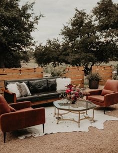 a living room filled with furniture next to a wooden fence and flowers on top of a table