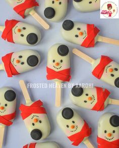 marshmallow snowman pops are arranged on a white surface with red ribbon around them