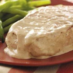 a red plate topped with meat covered in gravy next to asparagus