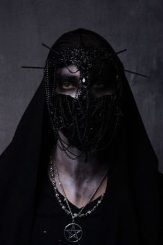 a man wearing a black mask with spikes on his head and chain around his neck