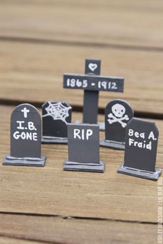 small tombstones decorated with black and white writing on wooden boards, sitting on top of a table