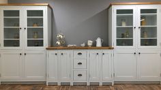 a white china cabinet with glass doors and wooden top in a living room next to a hardwood floor