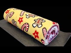 a roll covered in candy sitting on top of a black surface with red and white candies