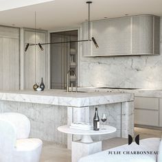 a kitchen with marble counter tops and white chairs in front of an island that has wine bottles on it