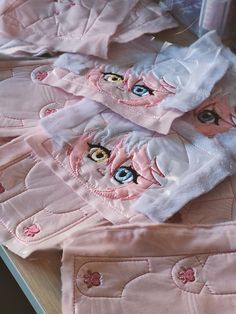 pink and white clothing with eyes on them sitting on top of a wooden table in front of a mirror