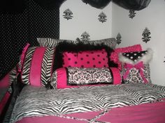 a zebra print bed with pink and black decor on it's headboard, along with polka dot pillows