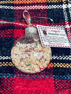 a christmas ornament hanging on a red and black plaid blanket with a tag that says merry christmas