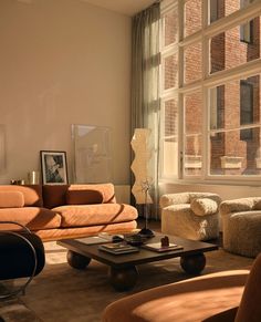 a living room filled with furniture next to a large window covered in sunlight streaming through the windows