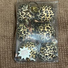 four leopard print ornaments in plastic package on carpet