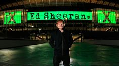 a man standing in front of a stadium with green lights on it's sides