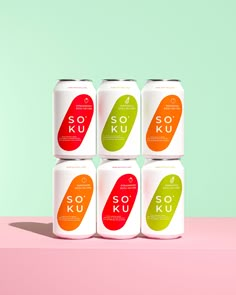 six cans of so ku are stacked on top of each other in front of a green and pink background