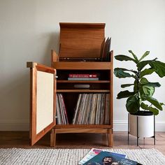 a record player sitting on top of a wooden cabinet next to a potted plant