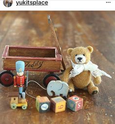 a teddy bear sitting on top of a wooden table next to toy animals and a wagon