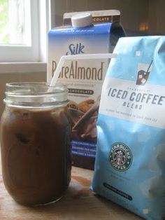 there is a jar of iced coffee next to a bag of cookies and a cup of coffee