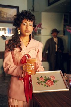 a woman in a pink dress holding a jar of honey and a framed picture with roses on it