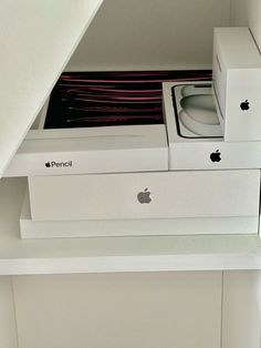 an apple computer sitting in a white box on top of a shelf next to a stack of plates