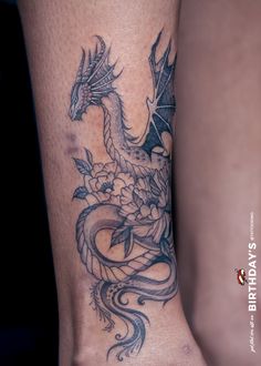 a woman's foot with a dragon and flowers tattoo on the side of her leg