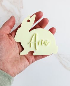 a person's hand holding an air freshener in the shape of a rabbit