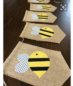 burlap tags with bees and polka dots hanging on a wooden table in the shape of hearts