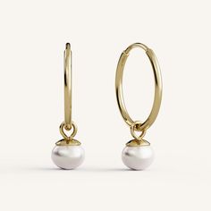 a pair of gold hoop earrings with white pearls on each ear and a single pearl hanging from the end