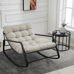 a chair and table in a room with white walls, rugs and flooring