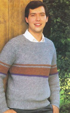 a young man is posing for a photo in front of a wooden wall wearing a sweater