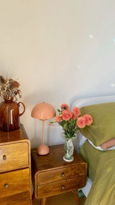 a bedroom with two nightstands and flowers on the night stand