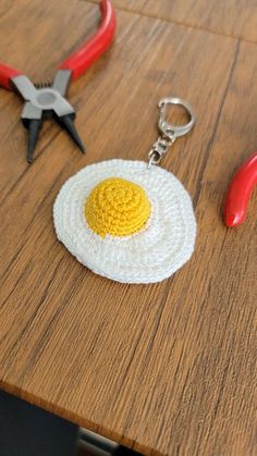 a crocheted fried egg keychain sitting on top of a wooden table