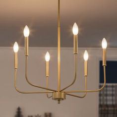 a chandelier with five lights hanging from it's center, in a living room