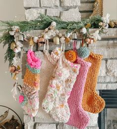 three knit stockings hanging from a mantel over a fireplace with christmas decorations on it