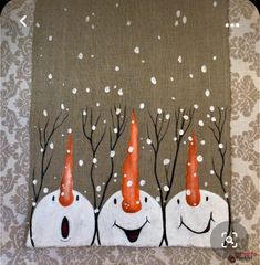 three snowmen with orange hats and trees