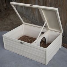 an open white box with some food in it on a concrete ground next to a fence