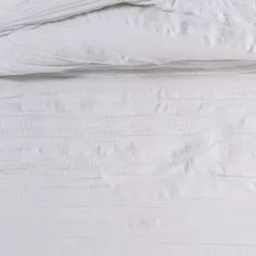 an unmade bed with white sheets and pillows