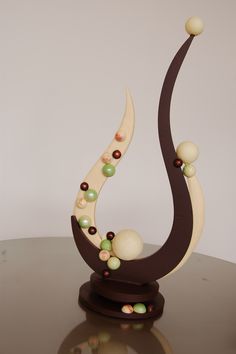 a sculpture is sitting on a table and has beads all over the top of it