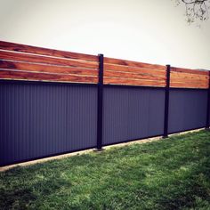 a wooden fence in the grass next to a tree