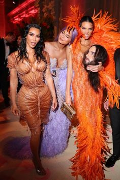 models pose for the camera at an event with other people wearing costumes and one man in a tuxedo