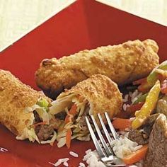 a red plate topped with meat, rice and veggies next to a fork