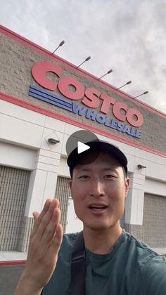 a man standing in front of a store with his hand up to the camera,