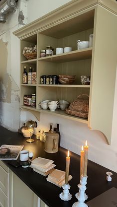 a kitchen counter topped with lots of shelves filled with dishes and candles on top of it